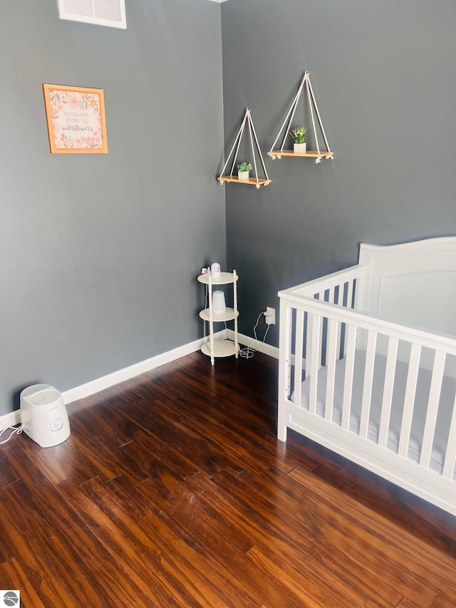 bedroom featuring a crib and hardwood / wood-style flooring