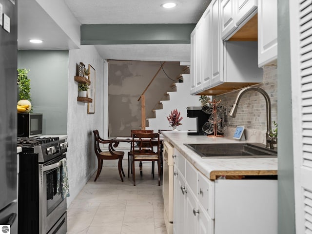 kitchen featuring dishwasher, white cabinets, decorative backsplash, gas stove, and sink