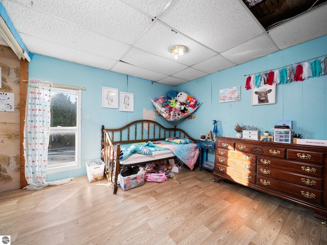 bedroom featuring a drop ceiling and light hardwood / wood-style flooring