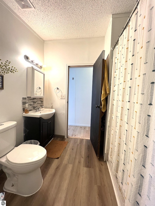 bathroom with vanity, a textured ceiling, toilet, hardwood / wood-style flooring, and decorative backsplash