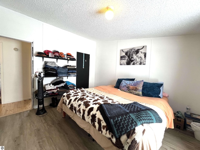 bedroom with a textured ceiling and dark hardwood / wood-style floors