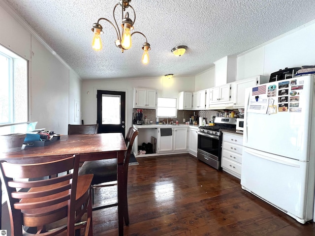 kitchen featuring hanging light fixtures, lofted ceiling, gas stove, white fridge, and white cabinetry