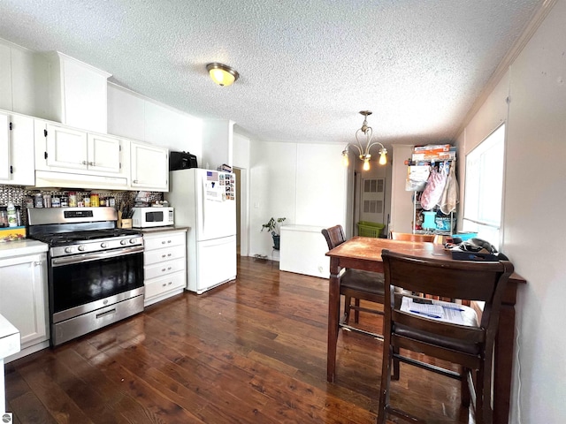 kitchen with dark wood-type flooring, white appliances, white cabinets, and decorative light fixtures