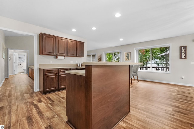 kitchen featuring light wood-type flooring, dark brown cabinets, a breakfast bar, and a center island