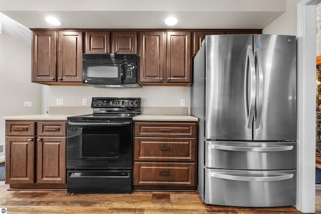 kitchen featuring dark brown cabinets, dark hardwood / wood-style floors, and black appliances