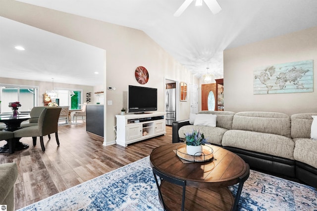 living room with ceiling fan, vaulted ceiling, and wood-type flooring