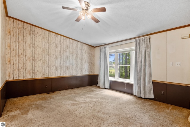 carpeted empty room with a textured ceiling, ceiling fan, and ornamental molding