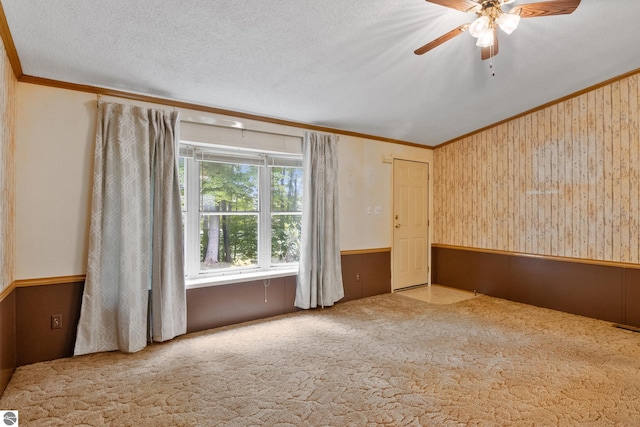 carpeted empty room featuring ceiling fan, vaulted ceiling, crown molding, and a textured ceiling