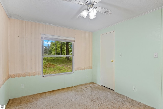 carpeted spare room featuring crown molding and ceiling fan