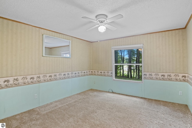 carpeted empty room with crown molding, ceiling fan, and a textured ceiling