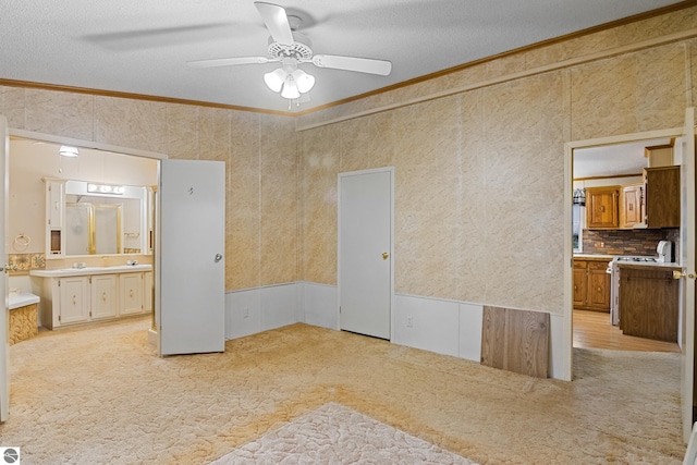 bedroom featuring a textured ceiling, ornamental molding, light colored carpet, and connected bathroom