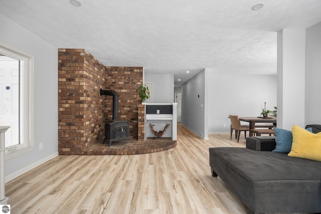 living room with a wood stove, a textured ceiling, and light hardwood / wood-style floors