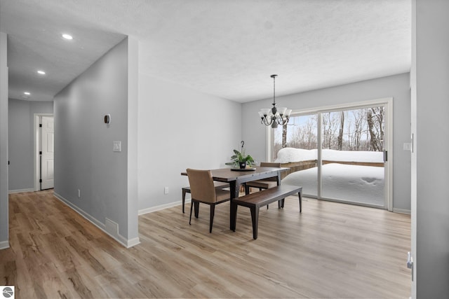 dining room featuring a textured ceiling, an inviting chandelier, and light hardwood / wood-style flooring