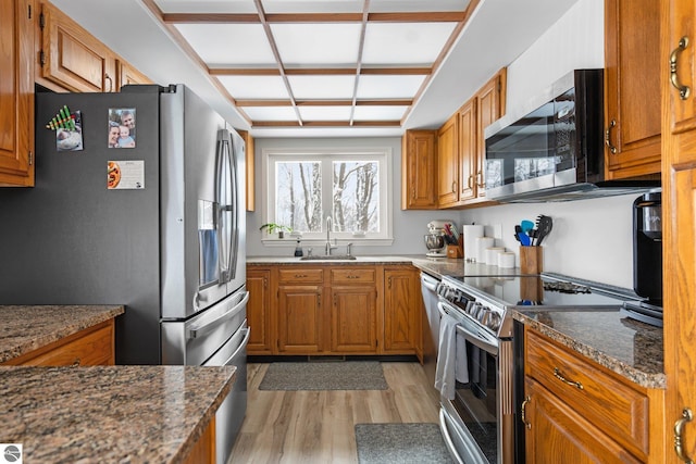 kitchen featuring light hardwood / wood-style floors, appliances with stainless steel finishes, sink, and dark stone counters