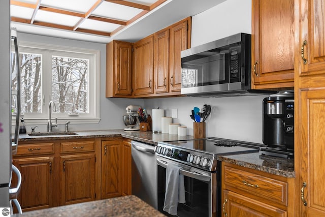 kitchen featuring stainless steel appliances, dark stone countertops, and sink