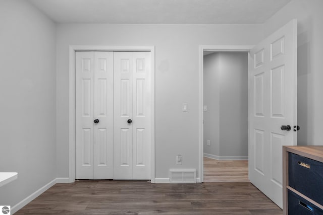 unfurnished bedroom featuring a closet and hardwood / wood-style floors