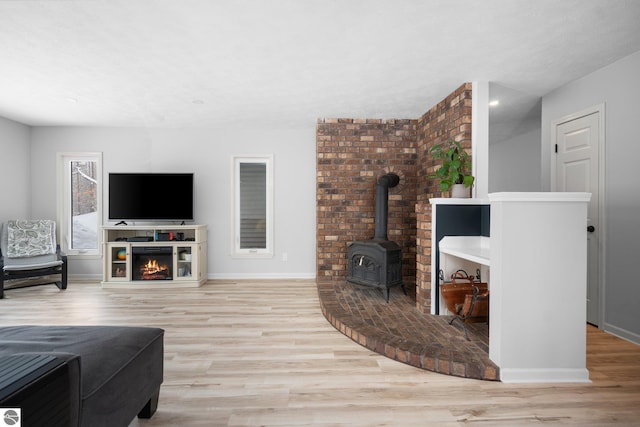 living room with a wood stove, a fireplace, and light hardwood / wood-style floors