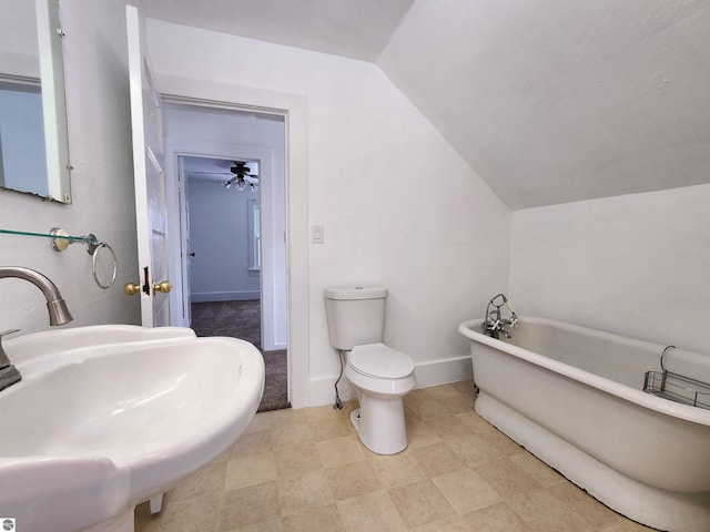 full bath featuring lofted ceiling, toilet, a sink, baseboards, and a soaking tub