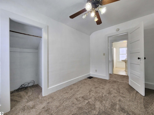 unfurnished bedroom featuring baseboards, lofted ceiling, ceiling fan, carpet floors, and a closet