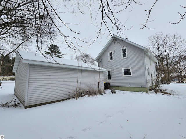 snow covered rear of property with a detached garage