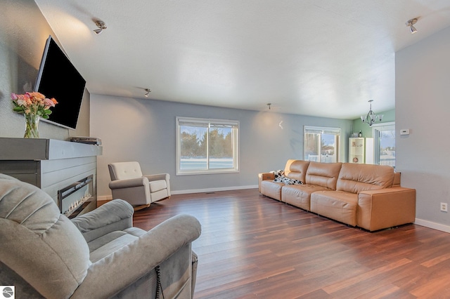 living area featuring a wealth of natural light, dark wood-style flooring, and a glass covered fireplace