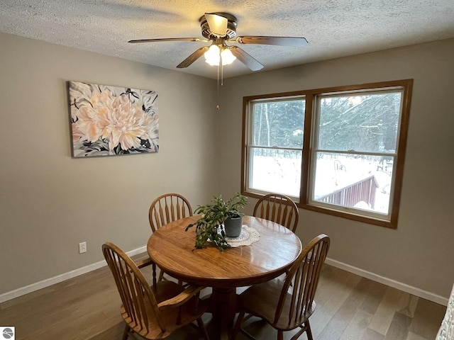 dining space with a textured ceiling, baseboards, and wood finished floors