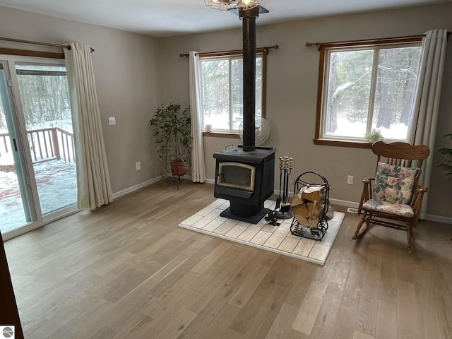 living area featuring a wood stove, light wood-style flooring, and baseboards