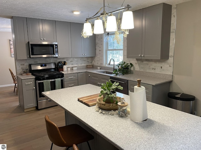 kitchen featuring a sink, stainless steel appliances, gray cabinets, and light countertops