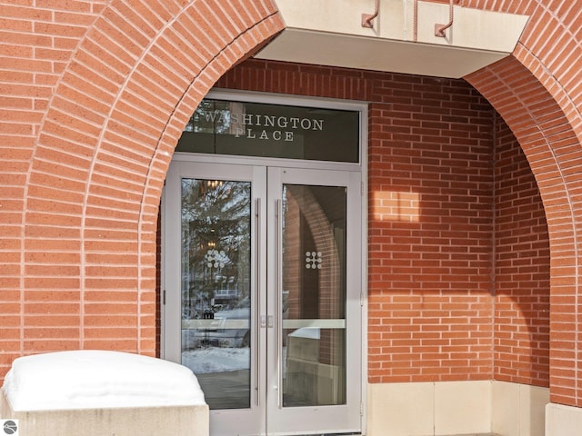 property entrance featuring french doors and brick siding