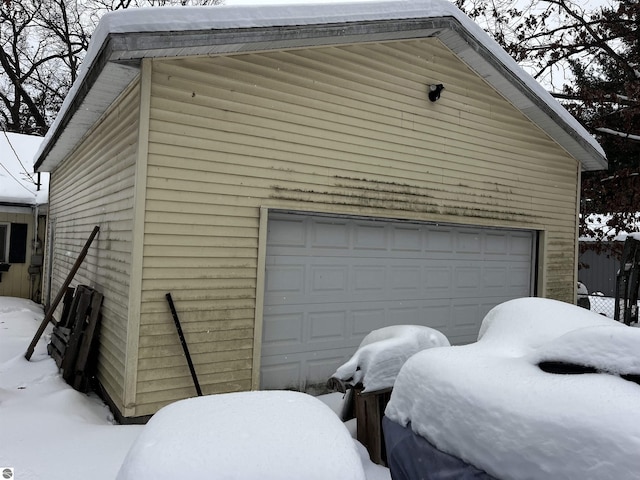 snow covered garage featuring a detached garage