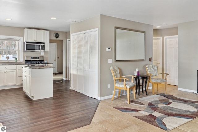 kitchen with white cabinets, dark countertops, a kitchen island, appliances with stainless steel finishes, and recessed lighting