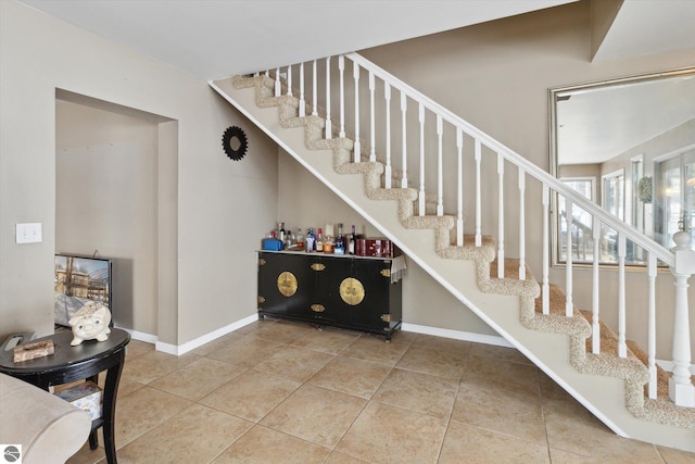 stairway with baseboards and tile patterned floors