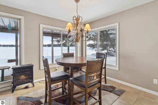 dining area with a wood stove, a healthy amount of sunlight, a water view, and a notable chandelier