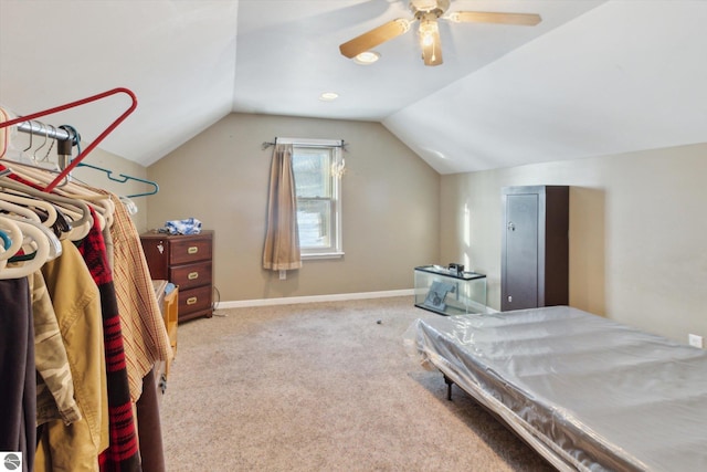 bedroom with a ceiling fan, light colored carpet, vaulted ceiling, and baseboards