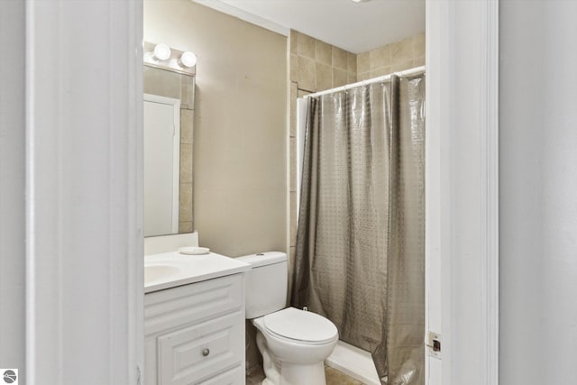 bathroom with a tile shower, vanity, and toilet