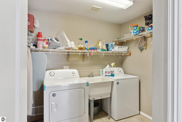 clothes washing area with laundry area, visible vents, a sink, and independent washer and dryer