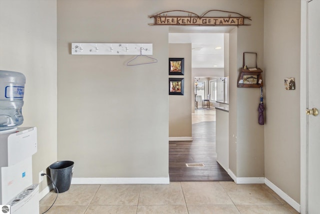 corridor with light tile patterned floors and baseboards