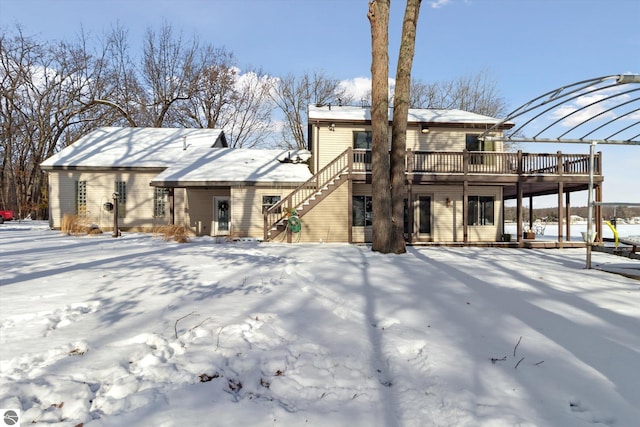 snow covered rear of property with a deck