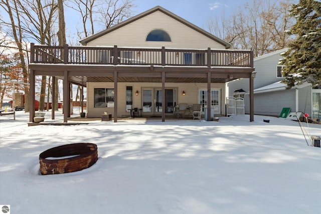 snow covered rear of property featuring a deck and a fire pit