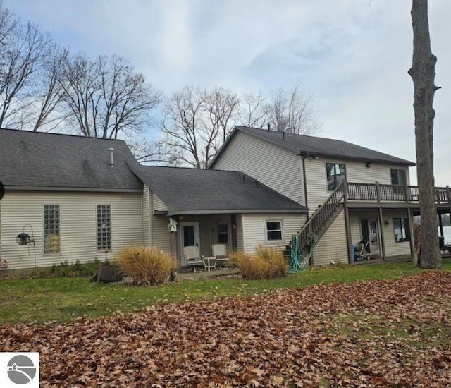 rear view of house featuring a lawn, stairway, and a wooden deck