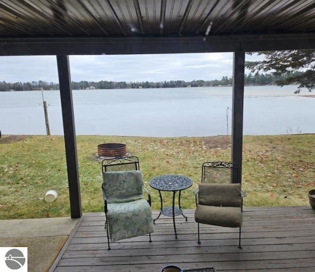 wooden terrace with an outdoor fire pit and a water view