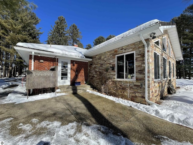 view of front facade featuring entry steps, stone siding, and brick siding