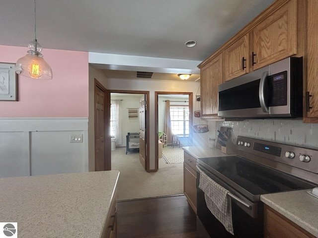 kitchen with stainless steel appliances, visible vents, hanging light fixtures, light countertops, and brown cabinetry