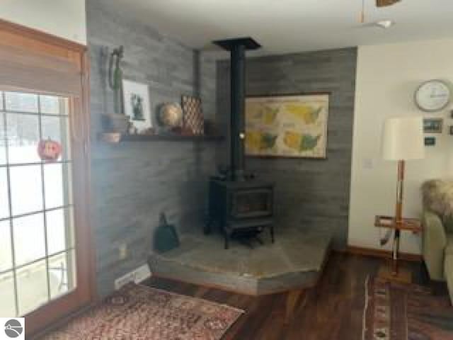 living room featuring a wood stove, baseboards, and wood finished floors