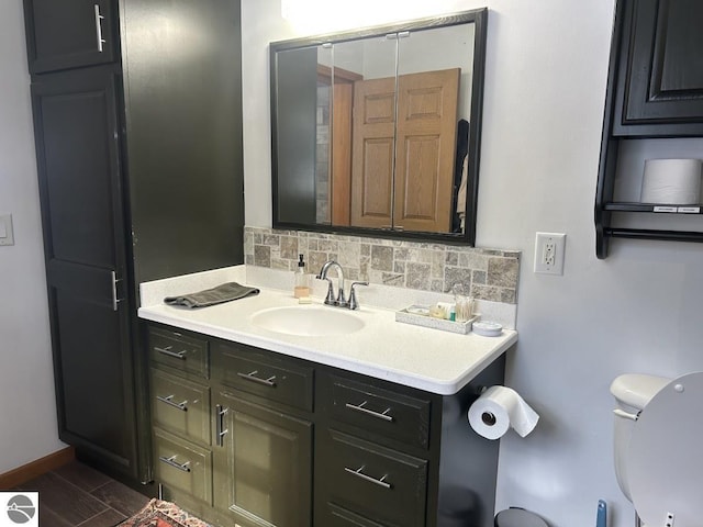 bathroom with tasteful backsplash, baseboards, toilet, wood finished floors, and vanity