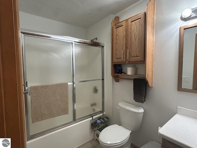 bathroom featuring toilet, bath / shower combo with glass door, and vanity