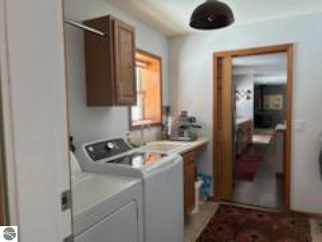 clothes washing area featuring separate washer and dryer and cabinet space