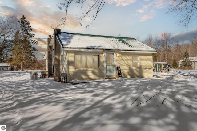 snow covered back of property with central AC