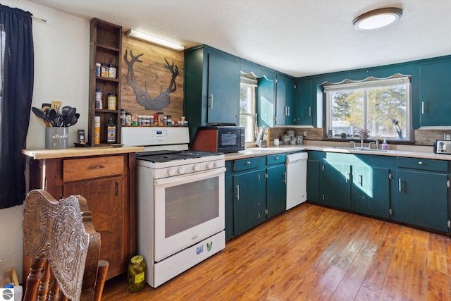 kitchen with light wood finished floors, light countertops, white appliances, and a sink