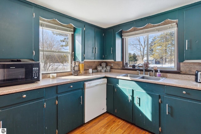 kitchen with black microwave, a sink, light wood-style floors, light countertops, and dishwasher